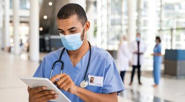 Mixed Race Nurse Using Digital Tablet At Hospital